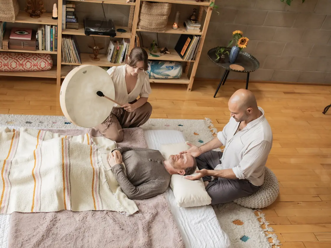 Yonatan offering Reiki at a resting client's head while a practitioner plays a frame drum, at the Word of Mouth studio in Los Angeles