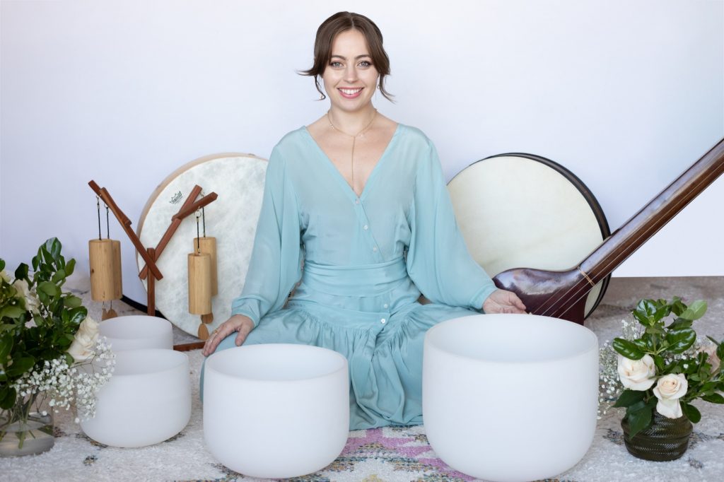 Jaime Elkayam smiling behind crystal singing bowls