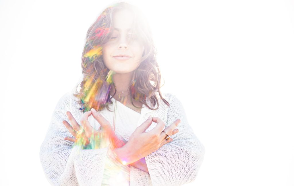 Jaime Elkayam smiling with eyes closed in rainbow prism light
