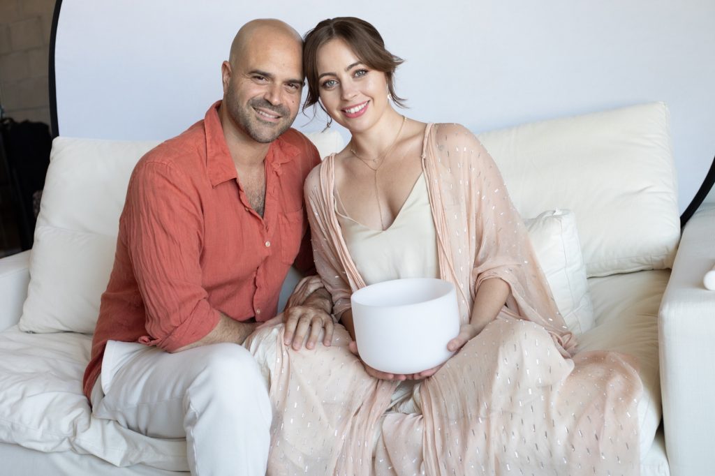 Jaime and Yonatan Elkayam heads together holding a crystal singing bowl