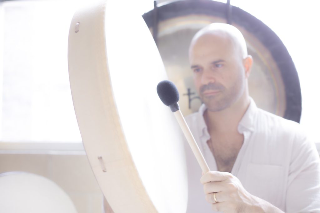 Yonatan Elkayam playing a frame drum with the gong behind him
