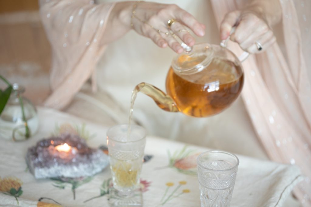 Tea pouring into a crystal glass by amethyst candlelight